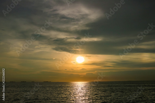 Bright sunset with large yellow sun under the sea surface. Sunset over sea landscape. Beautiful sunset with sky over calm sea in tropical island