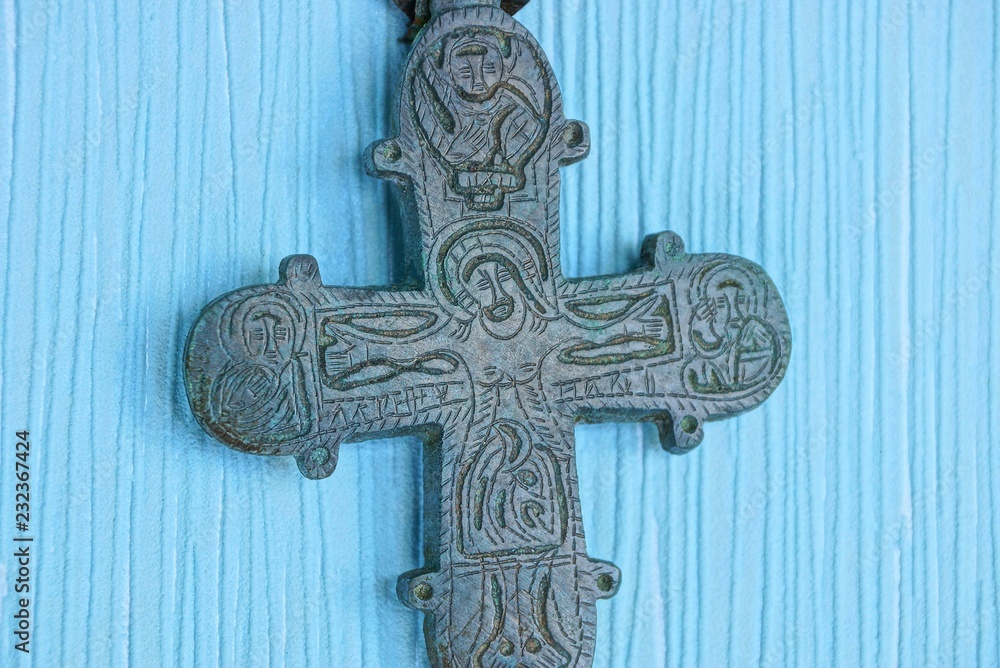 one old big bronze cross encolpion lies on a blue table