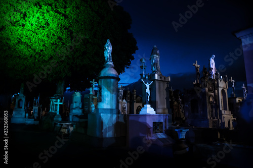 Dark blue lightened tombstones with huge tree during dawn in Cementerio General in Merida, Mexico photo