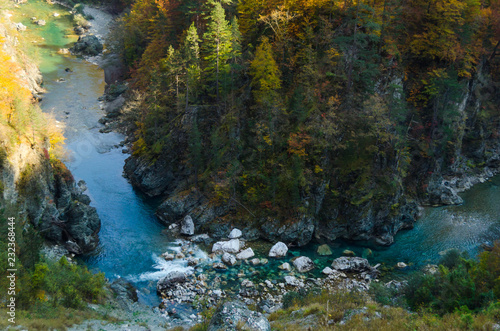 Drying up blue river flows deep in the canyon against the autumn forest.