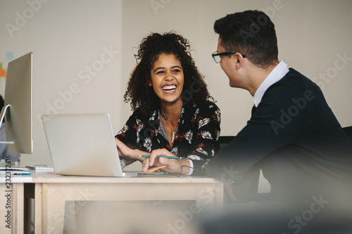 Smiling businesswoman discussing work with colleague in office photo