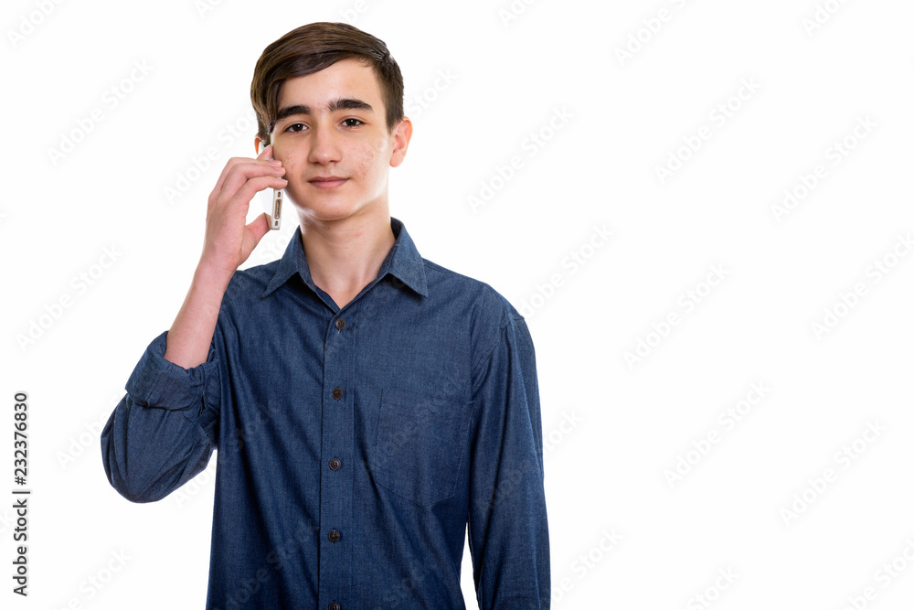 Studio shot of young handsome Persian teenage boy talking on mob Studio shot of young handsome Persian teenage boy talking on mob