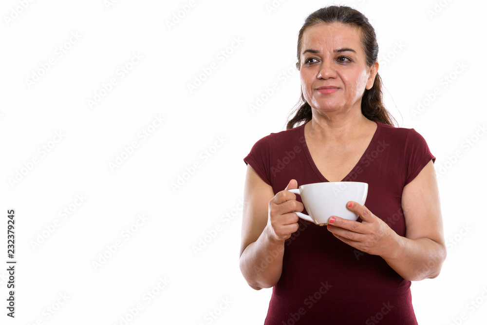 Studio shot of mature Persian woman thinking while holding coffe Studio shot of mature Persian woman thinking while holding coffe