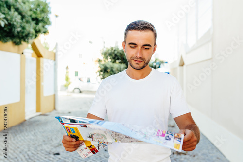 Fotografie Handsome man traveler found right direction on map walking with camera in urban setting