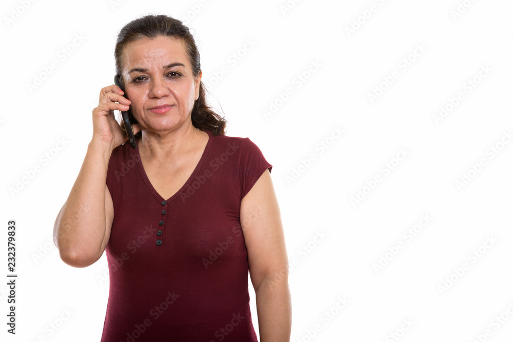 Studio shot of mature Persian woman talking on mobile phone Studio shot of mature Persian woman talking on mobile phone