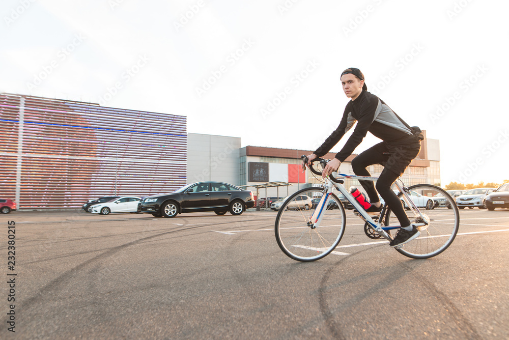 Φωτογραφία Portrait of a cute young man riding a parking lot on a background of modern architecture