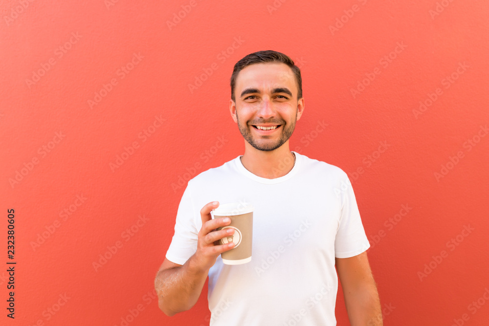 Handsome cool man with coffee cup to go isolated on red background Handsome cool man with coffee cup to go isolated on red background