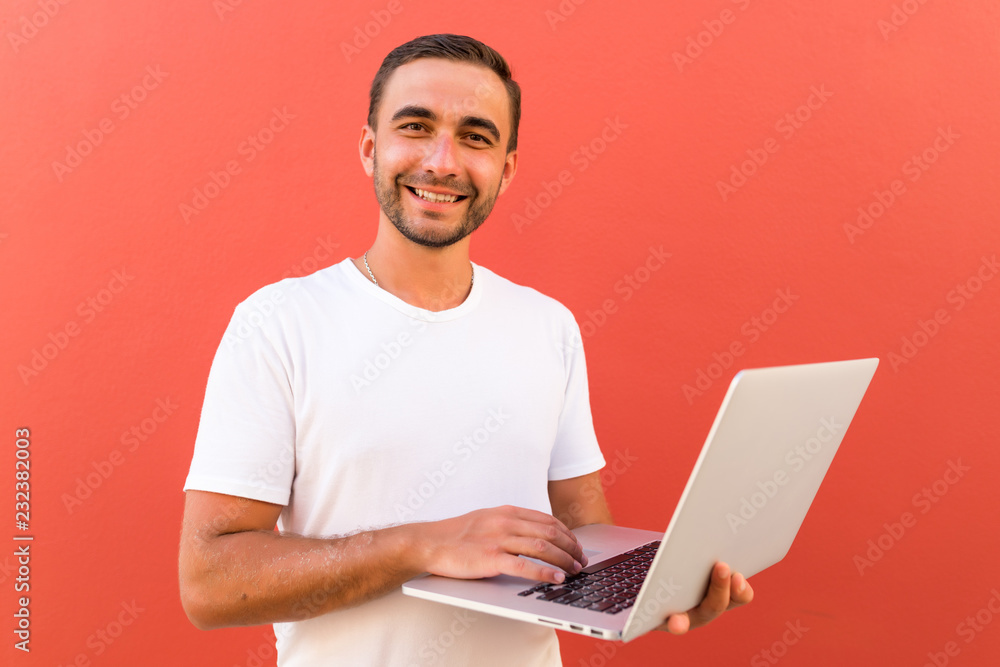 Handsome programmer man with laptop on red background Handsome programmer man with laptop on red background