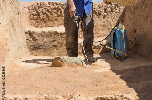 Specialized worker sprays an half-buried bronze piece at archaeological site photo