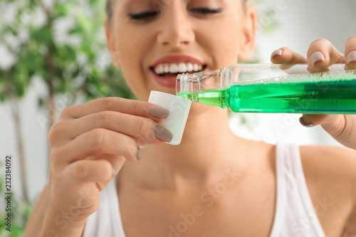 Woman pouring mouthwash from bottle into cap, closeup. Teeth care