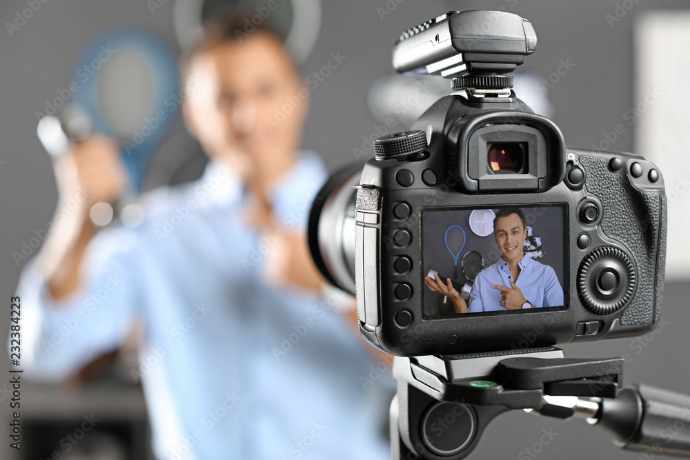 Sport blogger recording video indoors, selective focus on camera display. Space for text