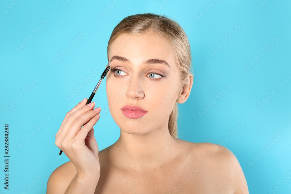 Portrait of young woman with beautiful natural eyelashes holding brush on color background Portrait of young woman with beautiful natural eyelashes holding brush on color background
