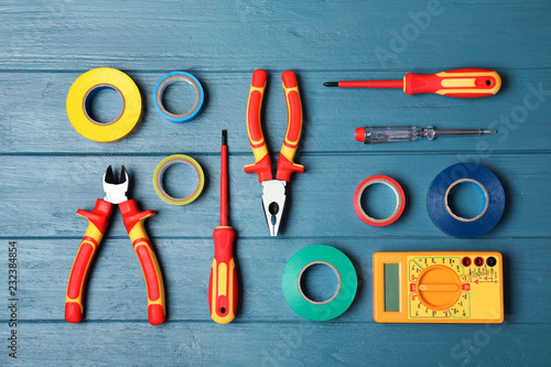 Flat lay composition with electrician's tools on wooden background photo