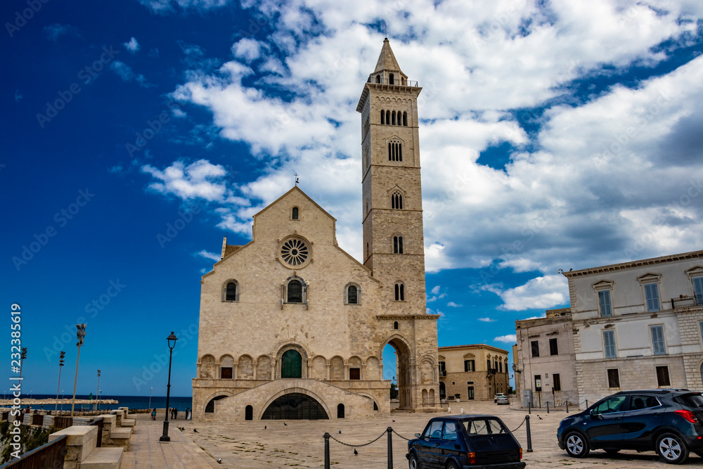 The beautiful Romanesque Cathedral Basilica of San Nicola Pellegrino, in Trani. Construction in limestone tuff stone, pink and white. vintage car parked. In Puglia, near Bari, Barletta, Andria, Italy.