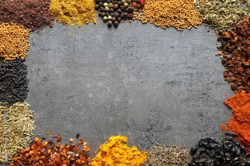 Frame made of different aromatic spices on gray background, top view with space for text