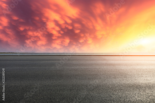 Asphalt road and dramatic sky with coastline at sunset © ABCDstock