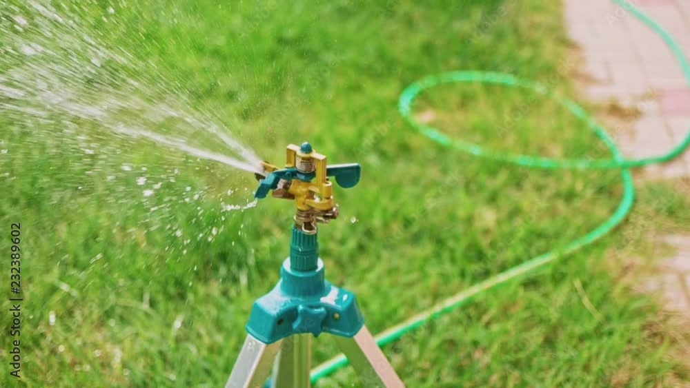 Working tripod garden sprinkler pan left in slow-motion Working tripod garden sprinkler pan left in slow-motion