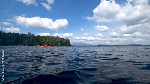 Kayaking on lake with Maine mountain fluffy summer clouds