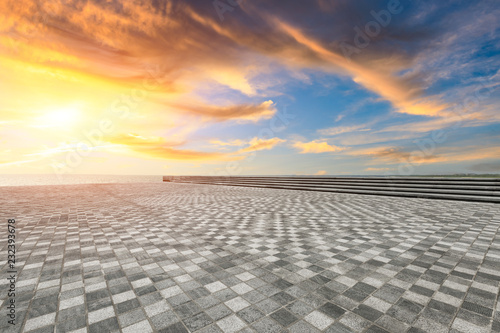 Empty square floor and dramatic sky with coastline at sunset