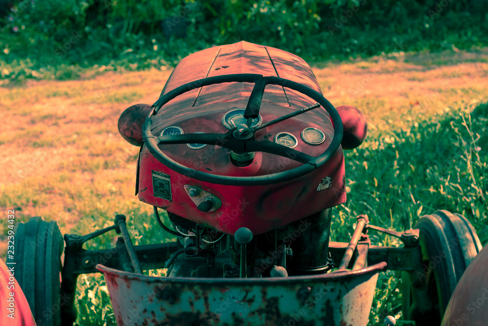 Little red tractor on a sunny fall day sitting in tall grass.