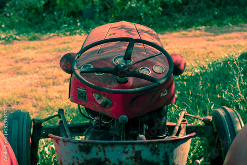 Obraz na płótnie Little red tractor on a sunny fall day sitting in tall grass. w salonie
