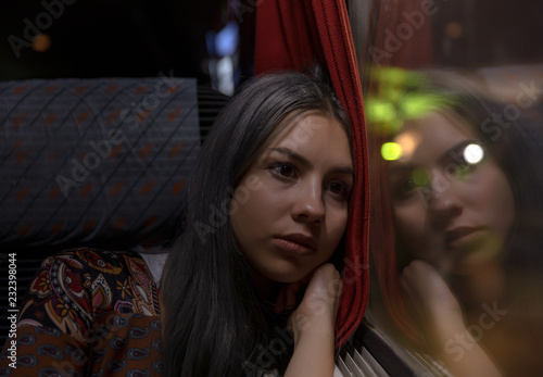 young thinking woman looking out of the train window at night