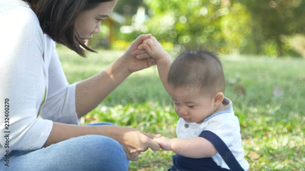Mother sitting with baby boy on green grass in the park, Happy family having a picnic in the green garden concept, Slow motion Mother sitting with baby boy on green grass in the park, Happy family having a picnic in the green garden concept, Slow motion