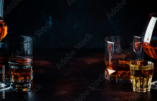 Selection of strong alcoholic drinks in glasses and shot glass in assortent: vodka, rum, cognac, tequila, brandy and whiskey. Dark vintage background, selective focus
