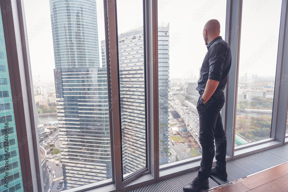 Young attractive stylish bald man in a business suit in his office in a skyscraper, business, finance, success Young attractive stylish bald man in a business suit in his office in a skyscraper, business, finance, success