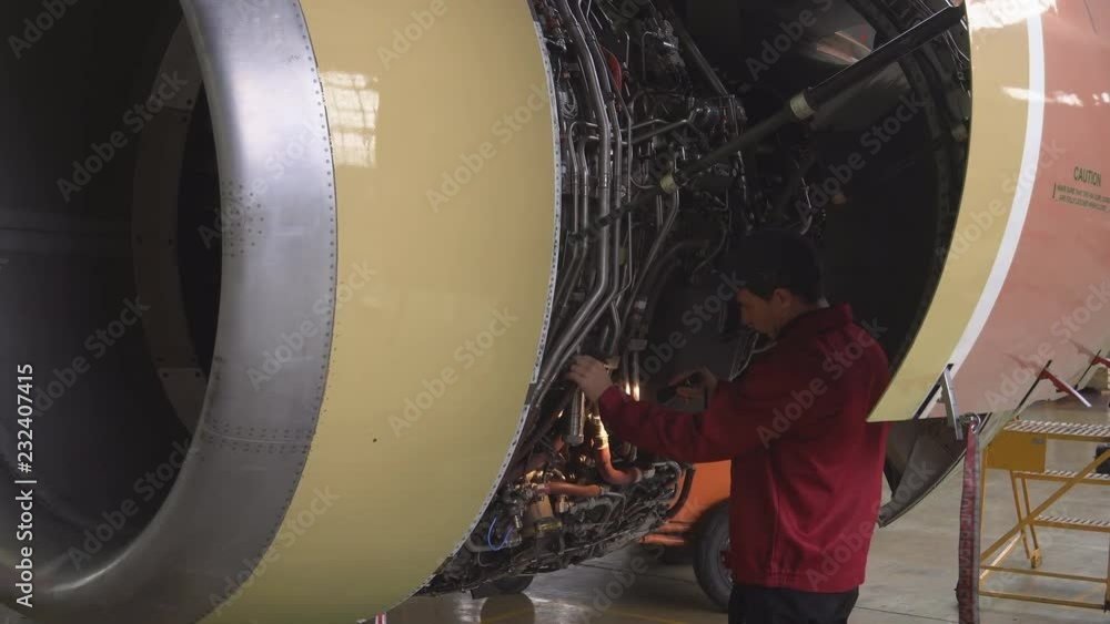 Engineer, technician examines the jet engine with a flashlight. The