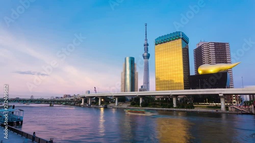 Colorful stationary time-lapse of daytime blue sky, evening red clouds sunset to dark night transition behind iconic Tokyo Skytree, Sumida-gawa river boat cruises near Azumabashi bridge. 4k at 30fps photo