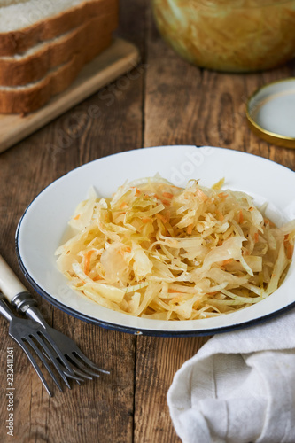 Sauerkraut with onions in a bowl on a wooden table