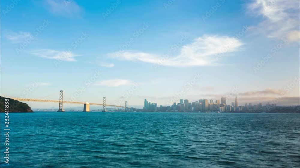 Stationary time-lapse transition from blue sky day to colorful sunset evening, night lights on San Francisco skyline cityscape, the Bay Bridge, viewed from Treasure Island across the bay. 4k at 30fps Stationary time-lapse transition from blue sky day to colorful sunset evening, night lights on San Francisco skyline cityscape, the Bay Bridge, viewed from Treasure Island across the bay. 4k at 30fps