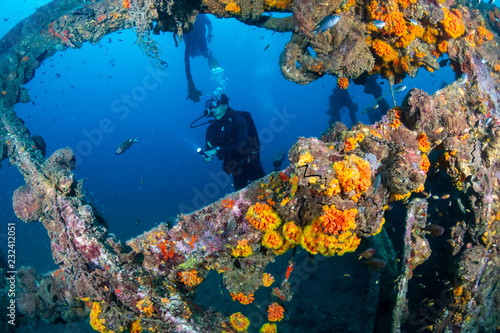 SCUBA diver exploring an old, coral encrusted underwater shipwreck in a tropical ocean (Boonsung, Thailand)