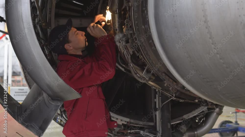 aircraft-maintenance-mechanic-with-a-flash-light-inspects-plane-engine