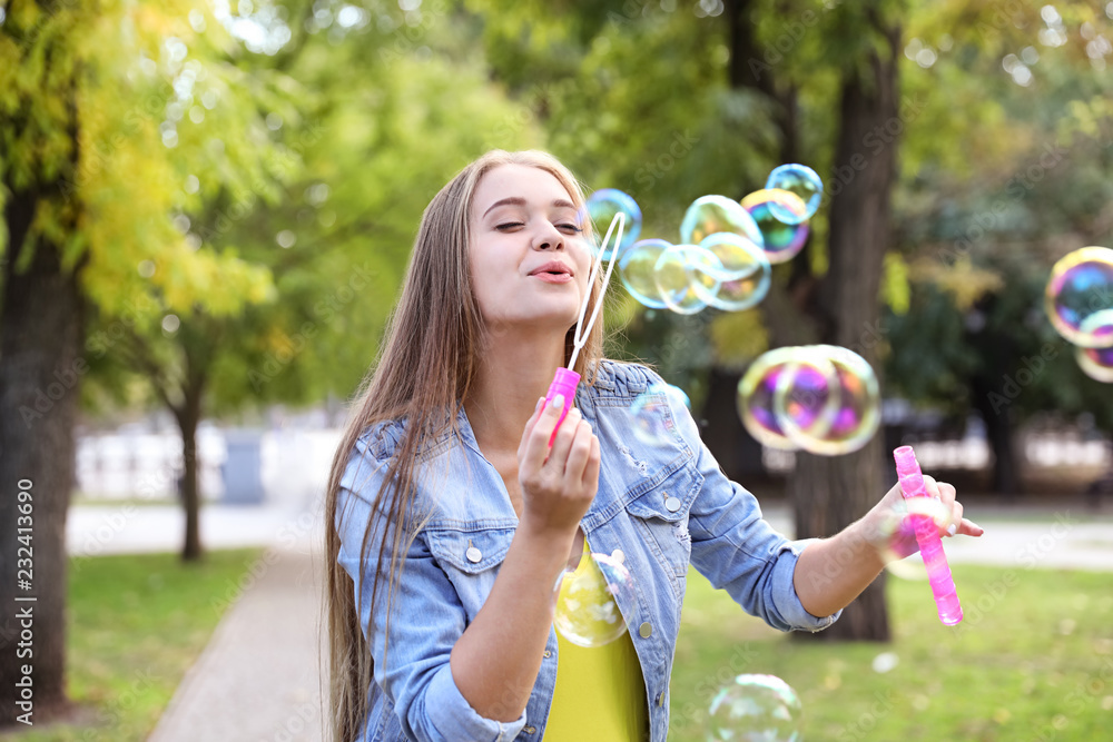 Young woman blowing soap bubbles in park Young woman blowing soap bubbles in park