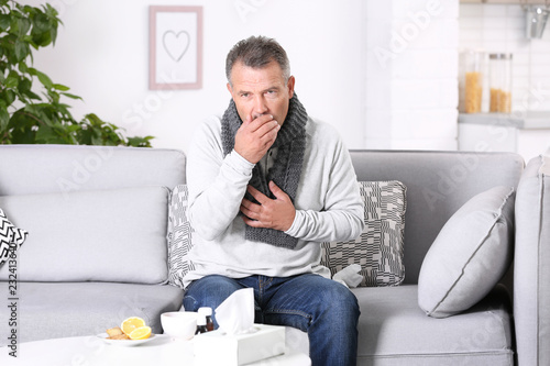 Man suffering from cough and cold on sofa at home