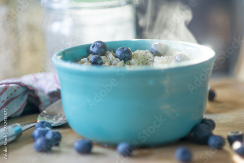 Canvas Print Bowel of hot steamy oatmeal with blueberries sits ready to eat.