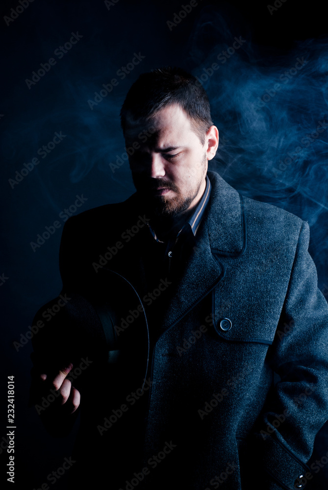 Fototapeta premium portrait of a man in a black coat on a dark background, Studio photo