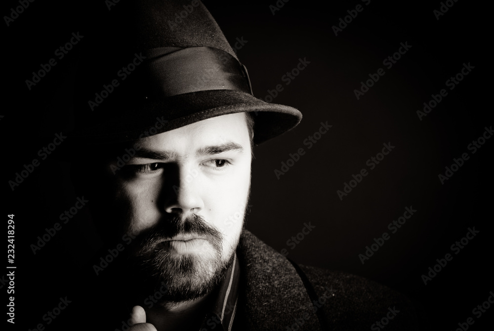 portrait of a man in a black hat and coat on a dark background, Studio photo portrait of a man in a black hat and coat on a dark background, Studio photo