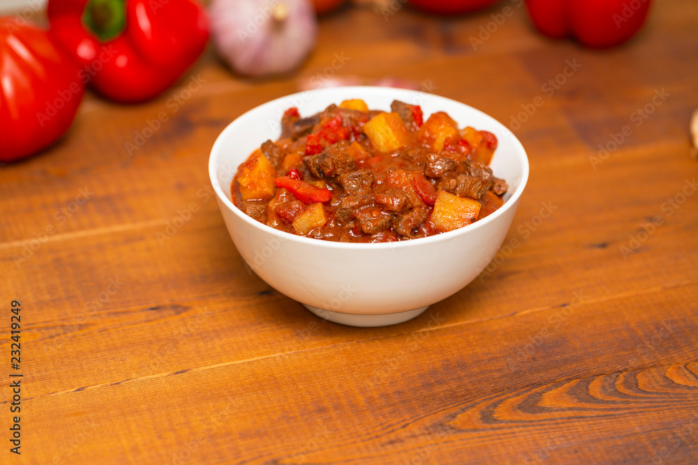 Meat stew with beef, potato, carrot, onion, spices,tomato and pepper . Slow cooked meat stew, bowl, wooden background. Hot autumn-winter dish. Close up. Meat stew with beef, potato, carrot, onion, spices,tomato and pepper . Slow cooked meat stew, bowl, wooden background. Hot autumn-winter dish. Close up.