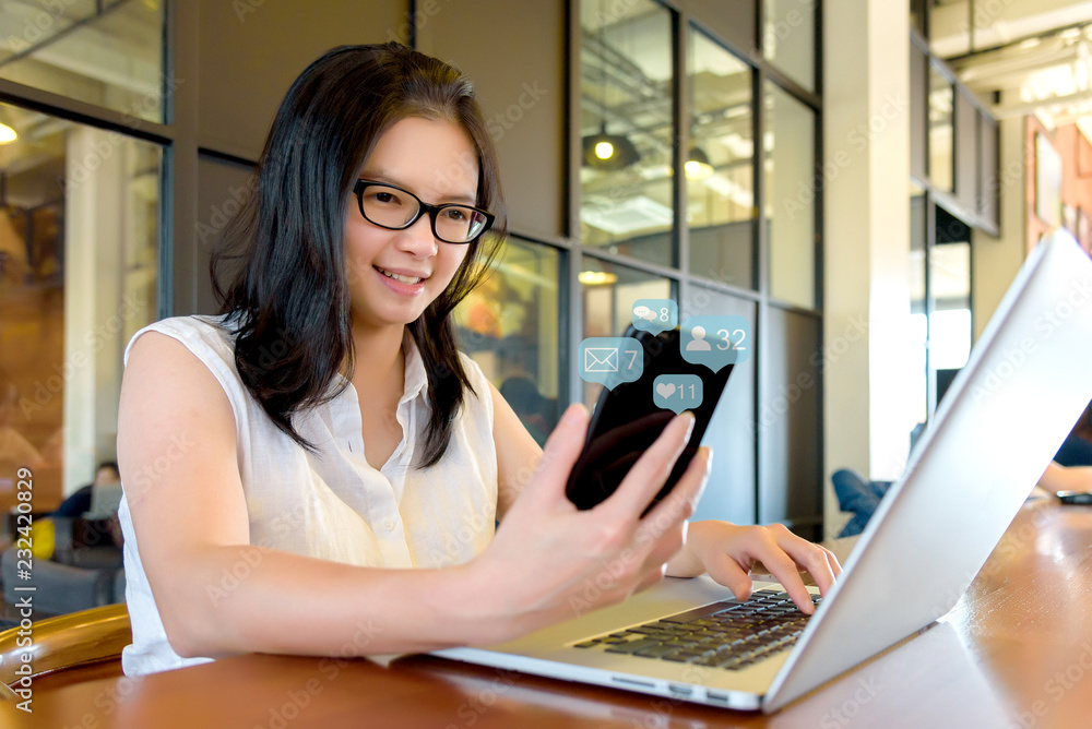 Asian charming beautiful girl freelancer in casual suit working or check information from website on her laptop and smartphone or mobile phone in coffee shop or modern office. Business Concept. Asian charming beautiful girl freelancer in casual suit working or check information from website on her laptop and smartphone or mobile phone in coffee shop or modern office. Business Concept.
