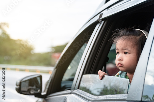 Tableau sur toile Asian little cute girl watching the nature beside the road with sadly face from the windows inside the car