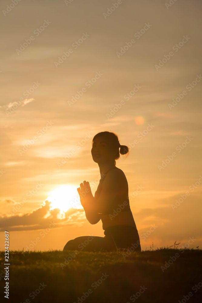 Fototapeta premium Young woman practicing yoga on the park at sunset, Silhouette