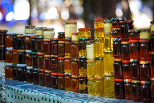 Banks with honey and jam are columns and rows in the window. Souvenirs for tourists in Georgia, yellow and red honey, jam from cones