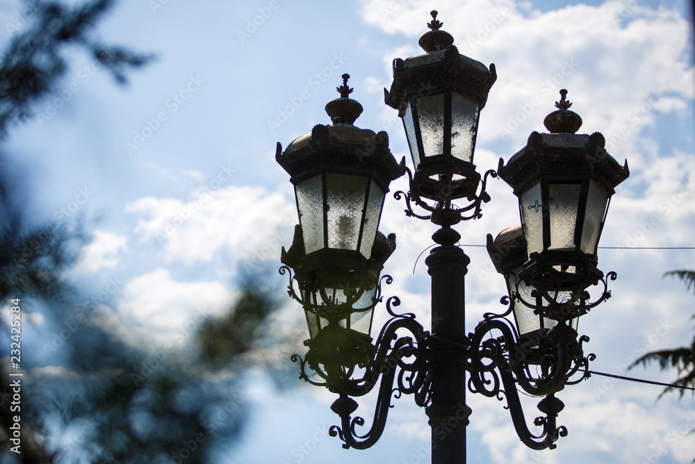 Antique street lamps in carved frames during the day. Pole with lights on the streets of Georgia in Borjomi