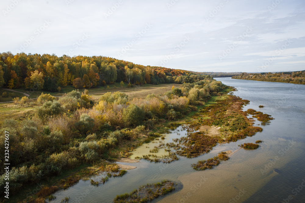 River valley in Russia, clear water with a sandy bottom, forest on the shore. Oka river in Russia in early autumn, the water surface, the turn of the river in the distance.