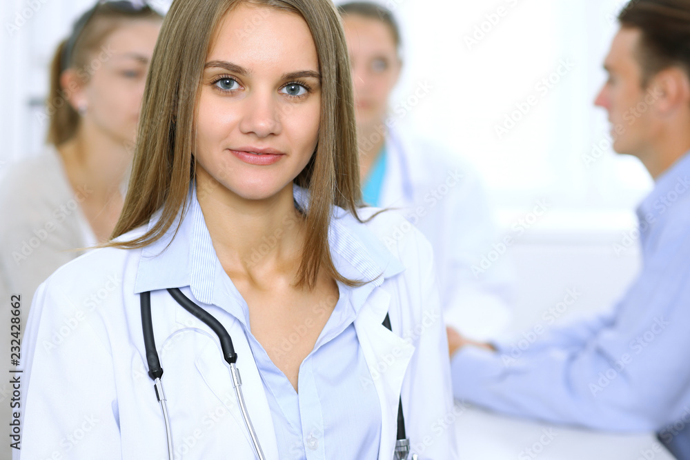 Happy doctor woman with medical staff at the background in hospital office Happy doctor woman with medical staff at the background in hospital office