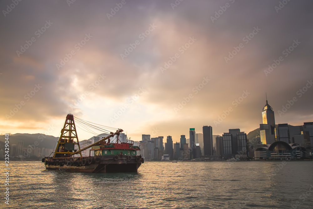 Cargo ship floating at the HongKong harbour with sunrise background.