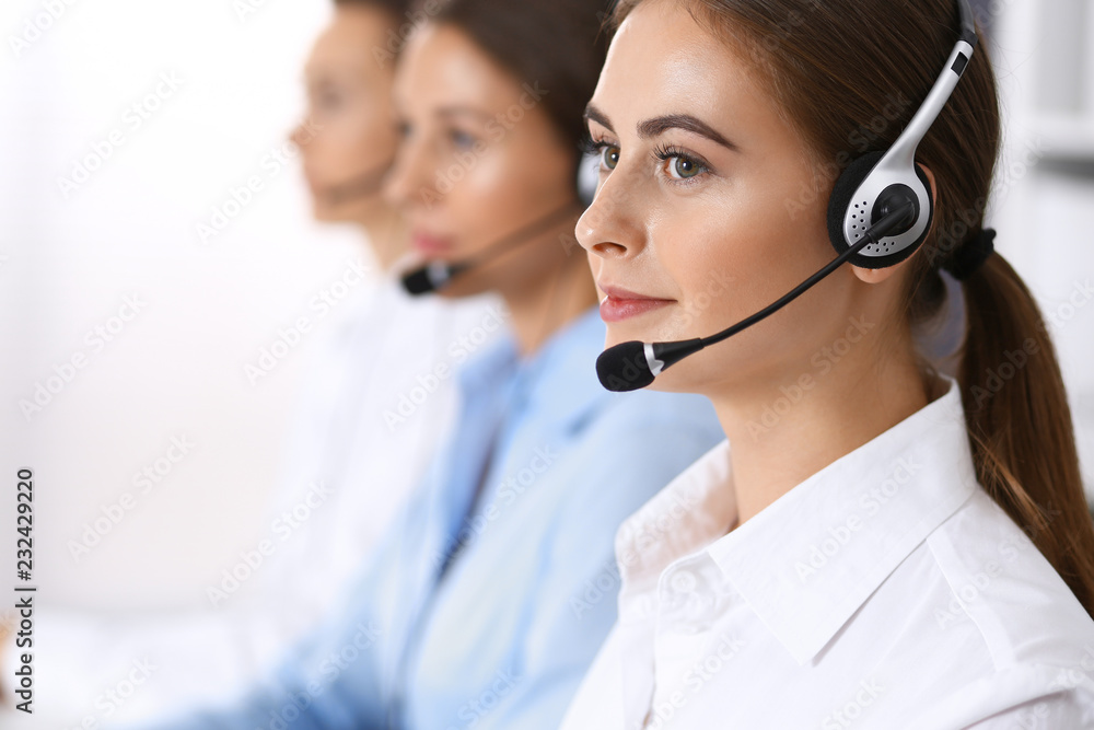 Call center. Group of operators at work. Focus on beautiful business woman in headset Call center. Group of operators at work. Focus on beautiful business woman in headset